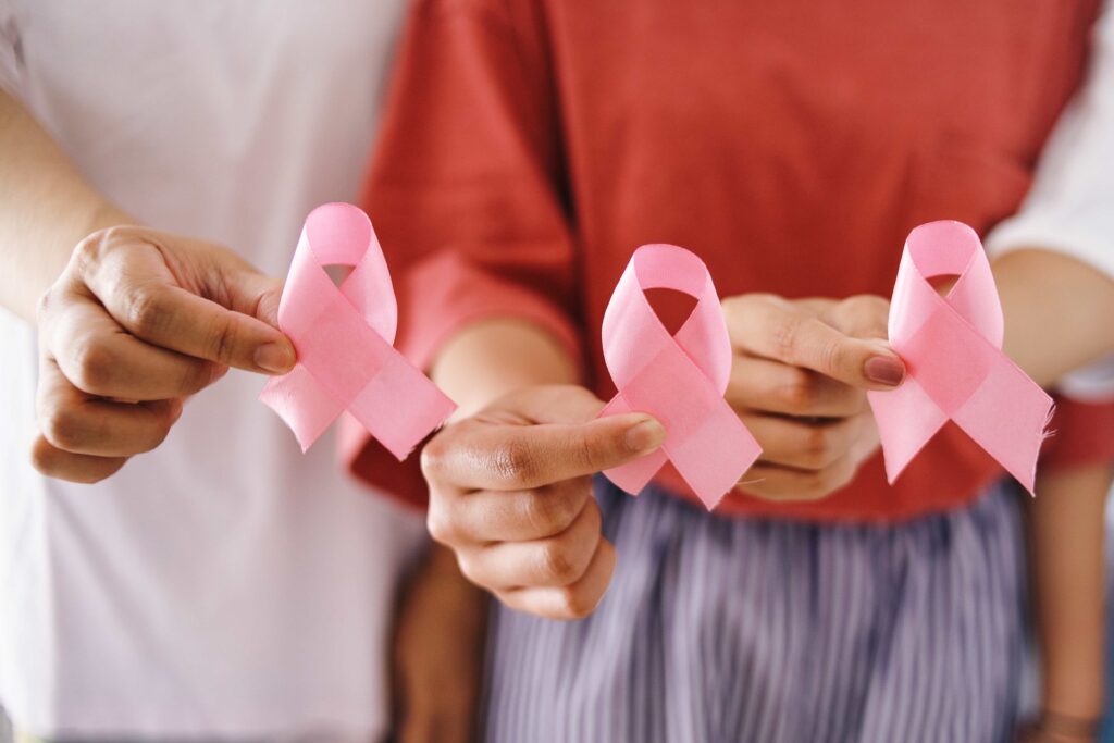 Três mãos femininas segurando laços símbolos do outubro rosa